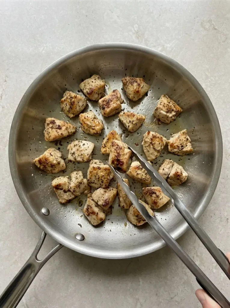 Chicken Gyro Bowls for a Fresh Mediterranean Dinner Chicken Gyro Bowls Browned lemon-herb chicken pieces cooking in a stainless-steel skillet